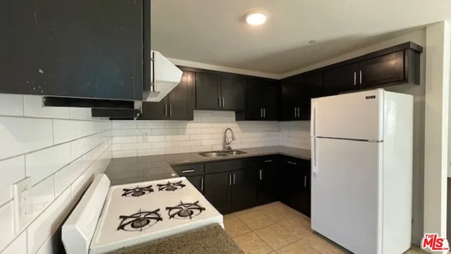 a kitchen with a sink a refrigerator and cabinets