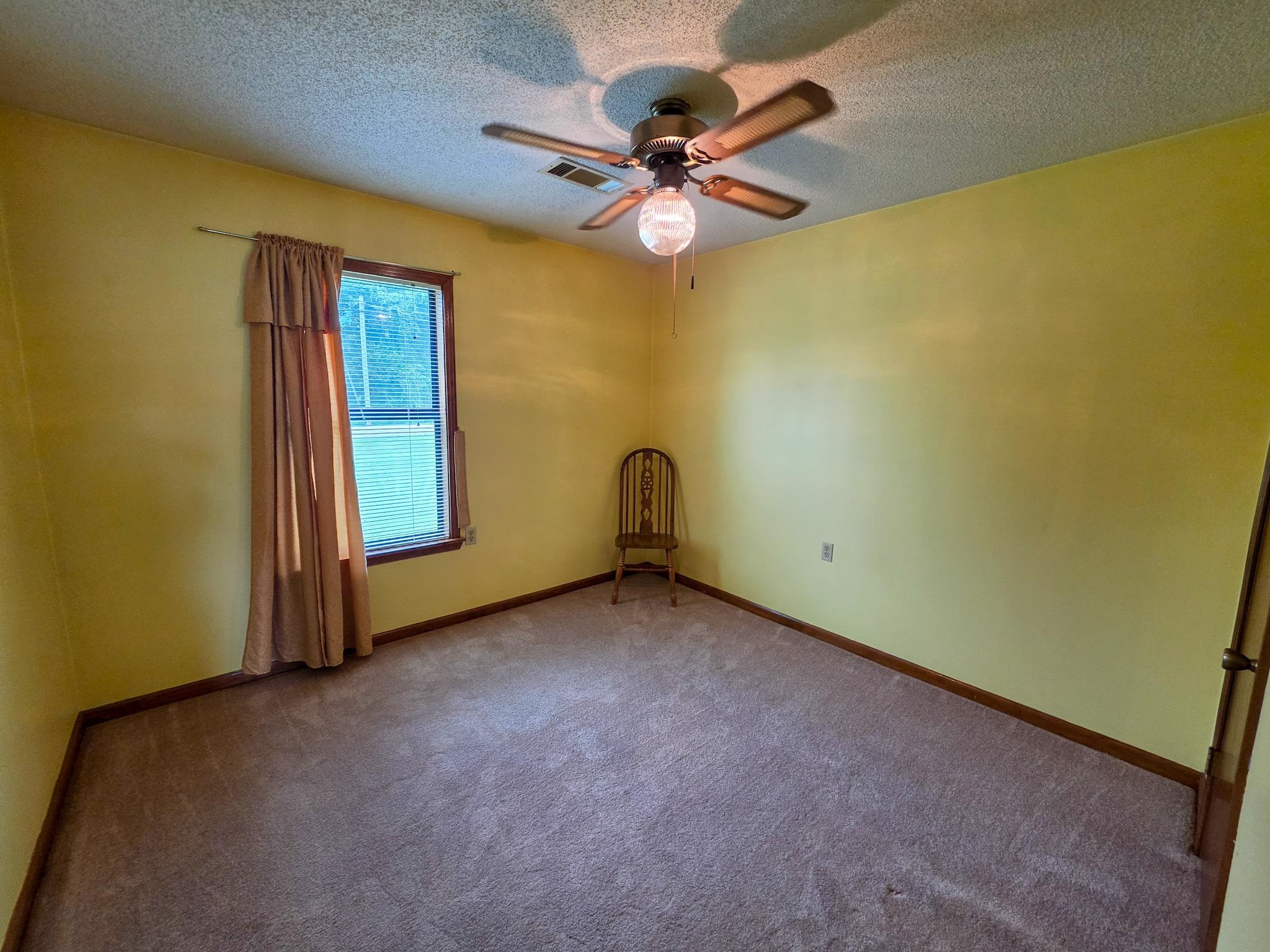 966 Beaver Road Munford, TN 38058 - Photo 17 of 32 Room with textured carpet flooring, a window featuring wood trim, and a ceiling fan with integrated lighting