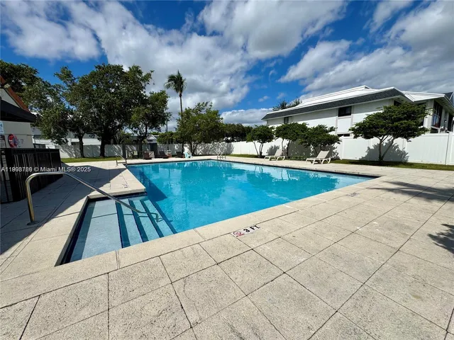 a view of swimming pool with seating space and trees in the background