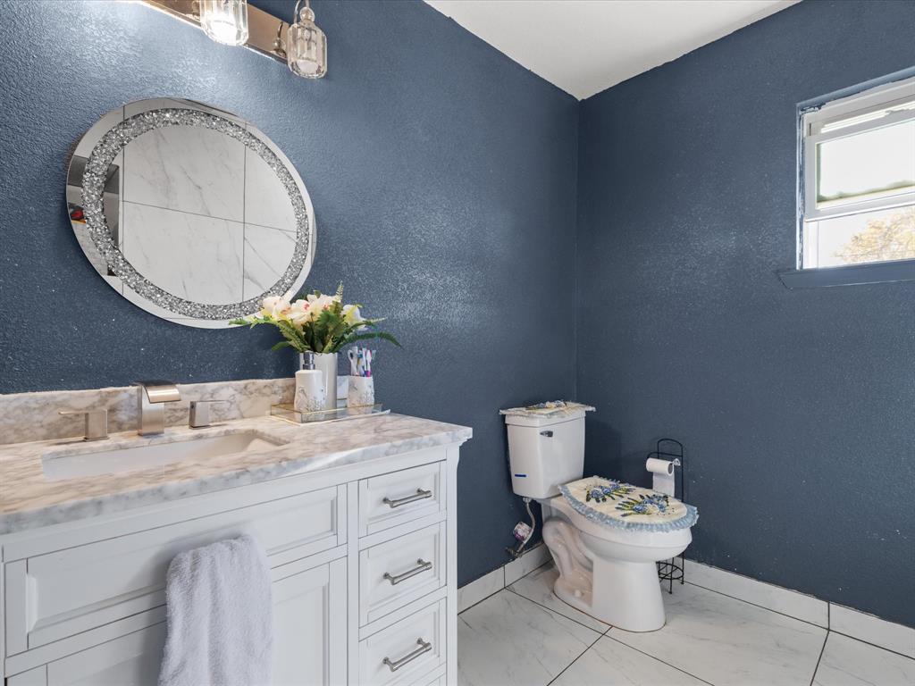 1805 Stevens Street Bridgeport, TX 76426 - Photo 14 of 24 a bathroom with a toilet mirror vanity and a window