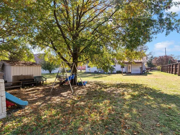 a view of backyard with wooden fence and large trees