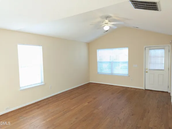 an empty room with wooden floor and windows
