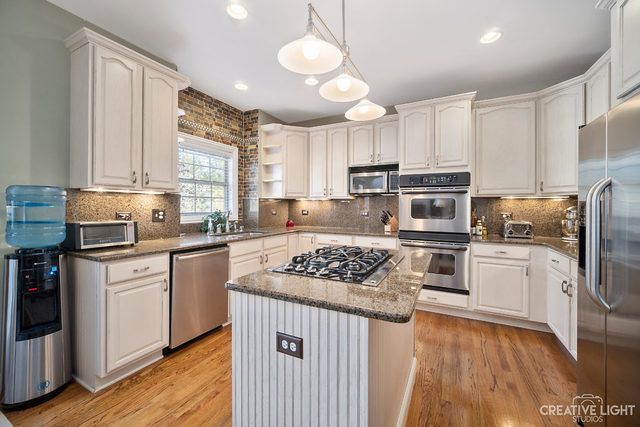 8 Winthrop New Road Sugar Grove, IL 60554 - Photo 14 of 38 a kitchen with stainless steel appliances granite countertop a stove top oven a refrigerator a sink and dishwasher with wooden floor