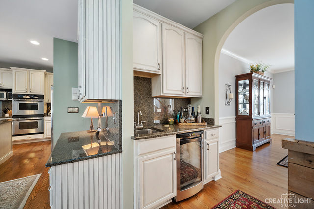 8 Winthrop New Road Sugar Grove, IL 60554 - Photo 7 of 38 a kitchen with stainless steel appliances granite countertop a stove top oven a sink a refrigerator and white cabinets with wooden floor