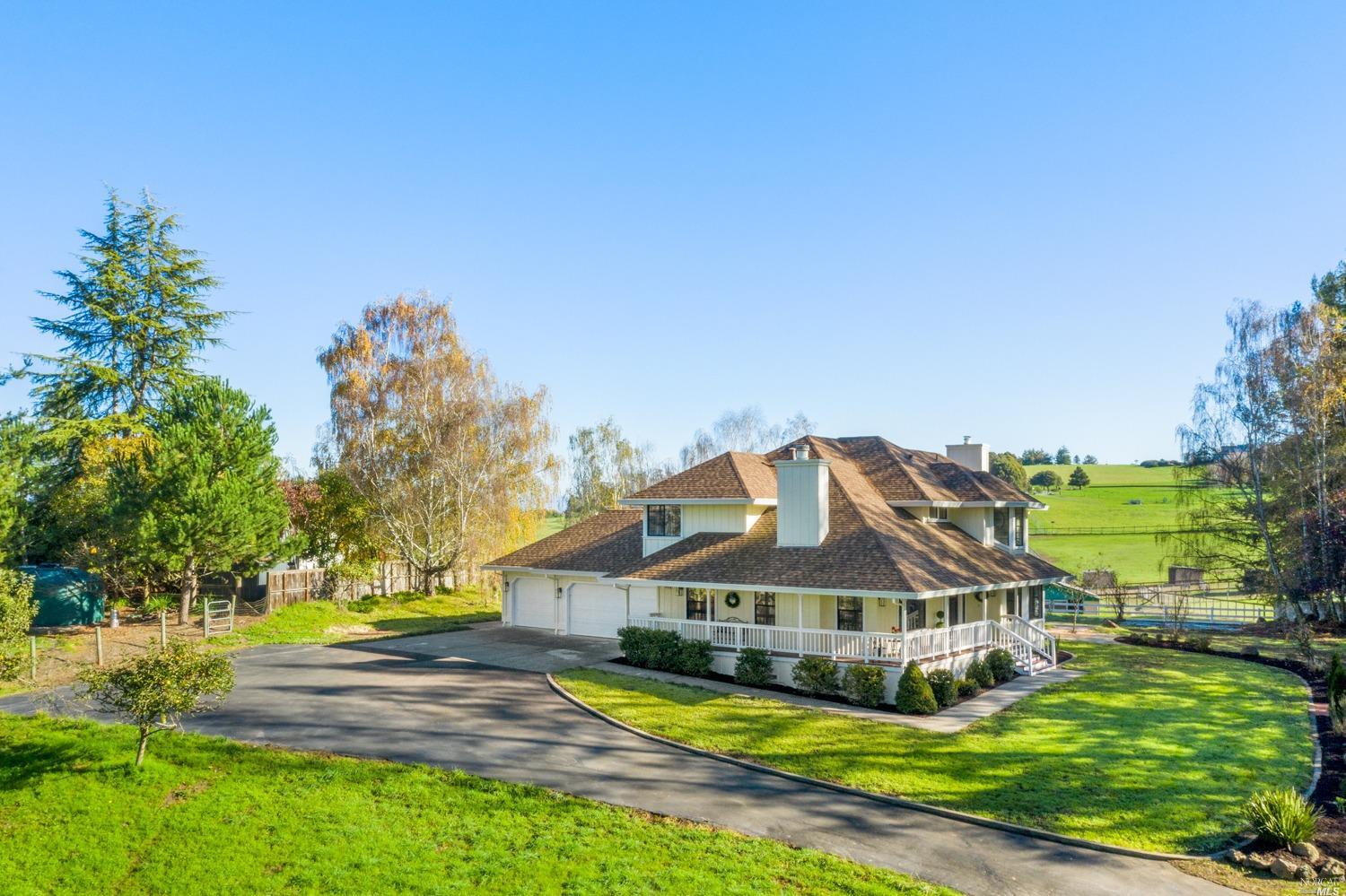 a view of a big house with a big yard and large trees