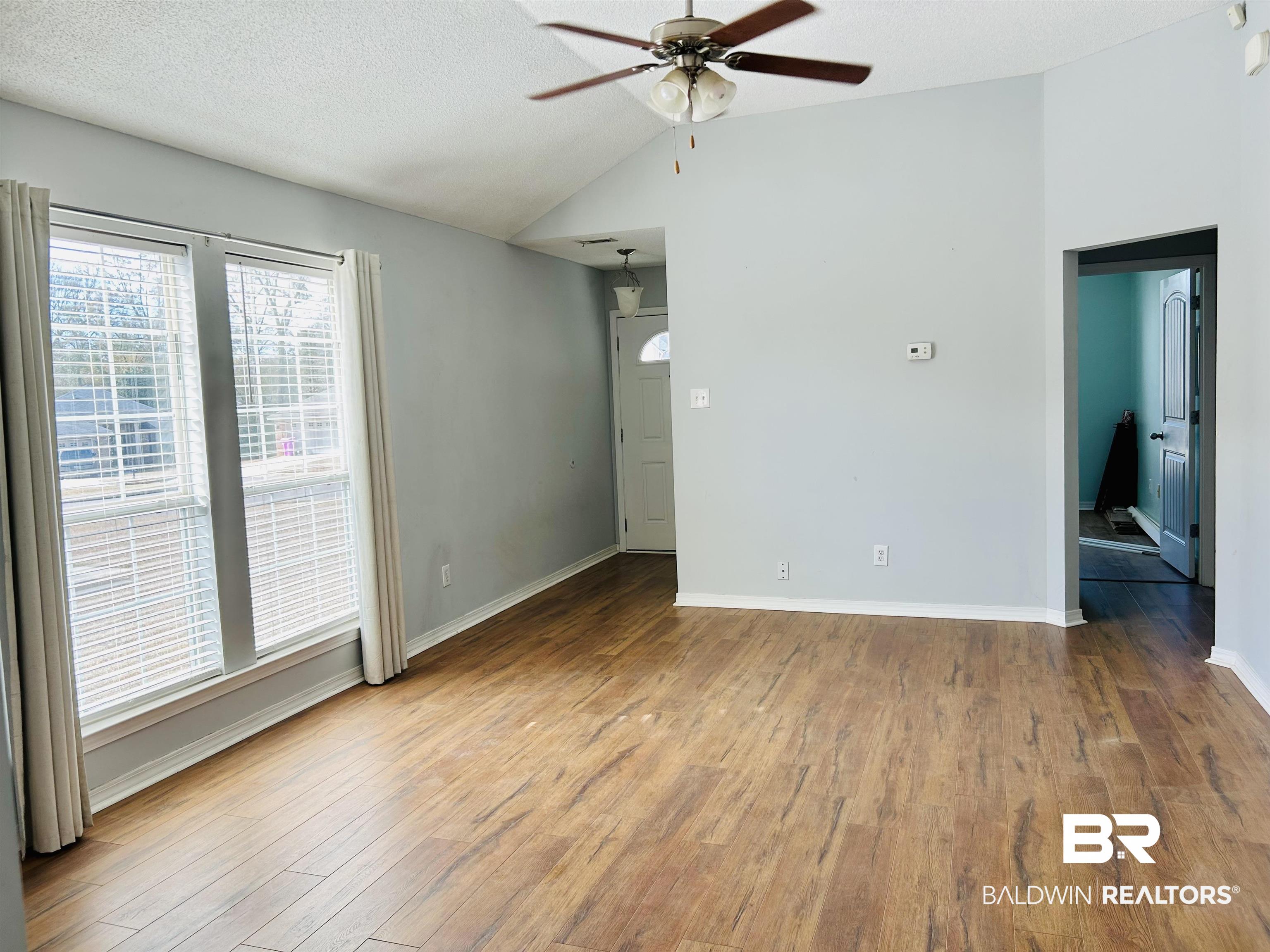 919 Parliament Court Mobile, AL 36695 - Photo 6 of 19 Unfurnished room featuring wood-type flooring, vaulted ceiling, ceiling fan, and a textured ceiling