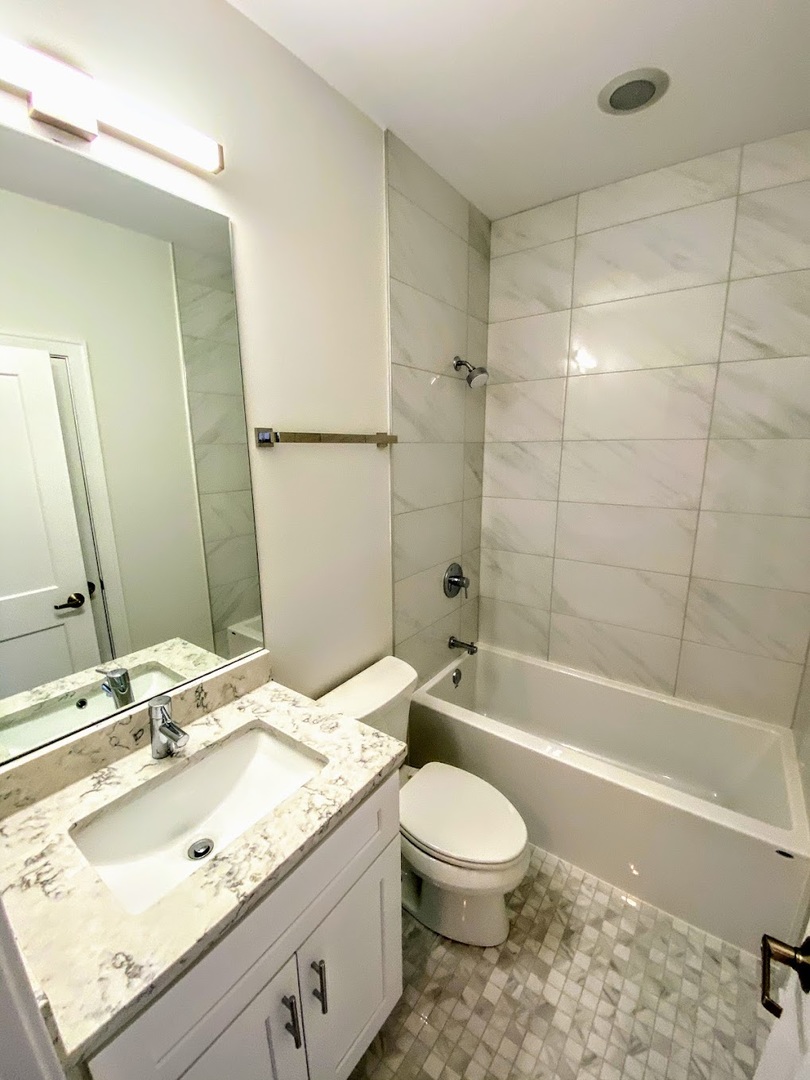 3203 North Ridgeway Avenue, Unit 2B Chicago, IL 60618 - Photo 11 of 15 a bathroom with a granite countertop sink a toilet and shower