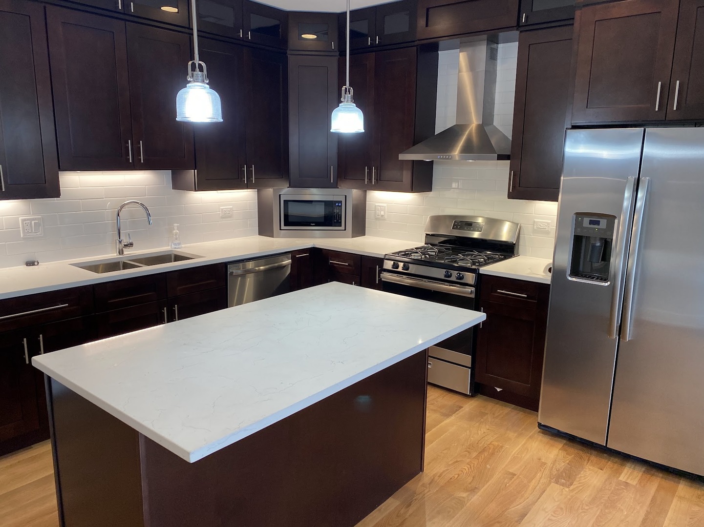 3203 North Ridgeway Avenue, Unit 2B Chicago, IL 60618 - Photo 4 of 15 a kitchen with stainless steel appliances a sink a stove a refrigerator a center island and chairs