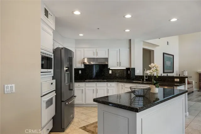 a kitchen with stainless steel appliances granite countertop a sink a stove and a refrigerator