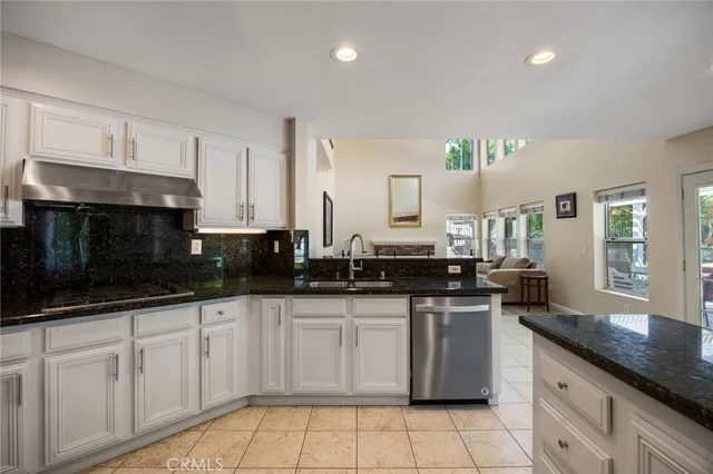 a kitchen with granite countertop a sink a stove and cabinets