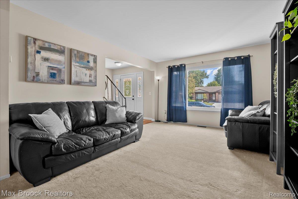 42470 Bishop Road Canton, MI 48188 - Photo 5 of 37 Carpeted living area with a large window, light-colored walls, and a front entry door with decorative glass panels