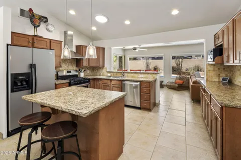 a kitchen with stainless steel appliances granite countertop table chairs sink refrigerator and stove
