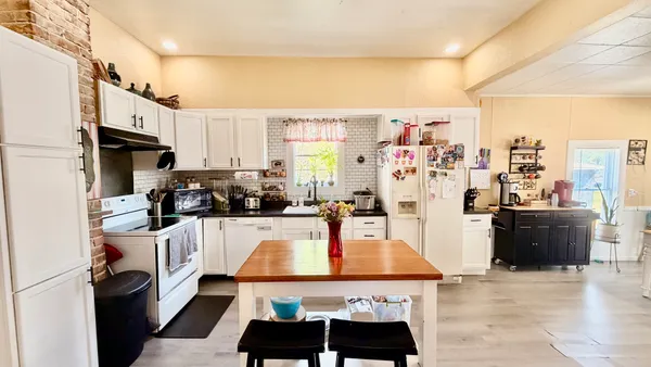 a living room with furniture a large window and kitchen view
