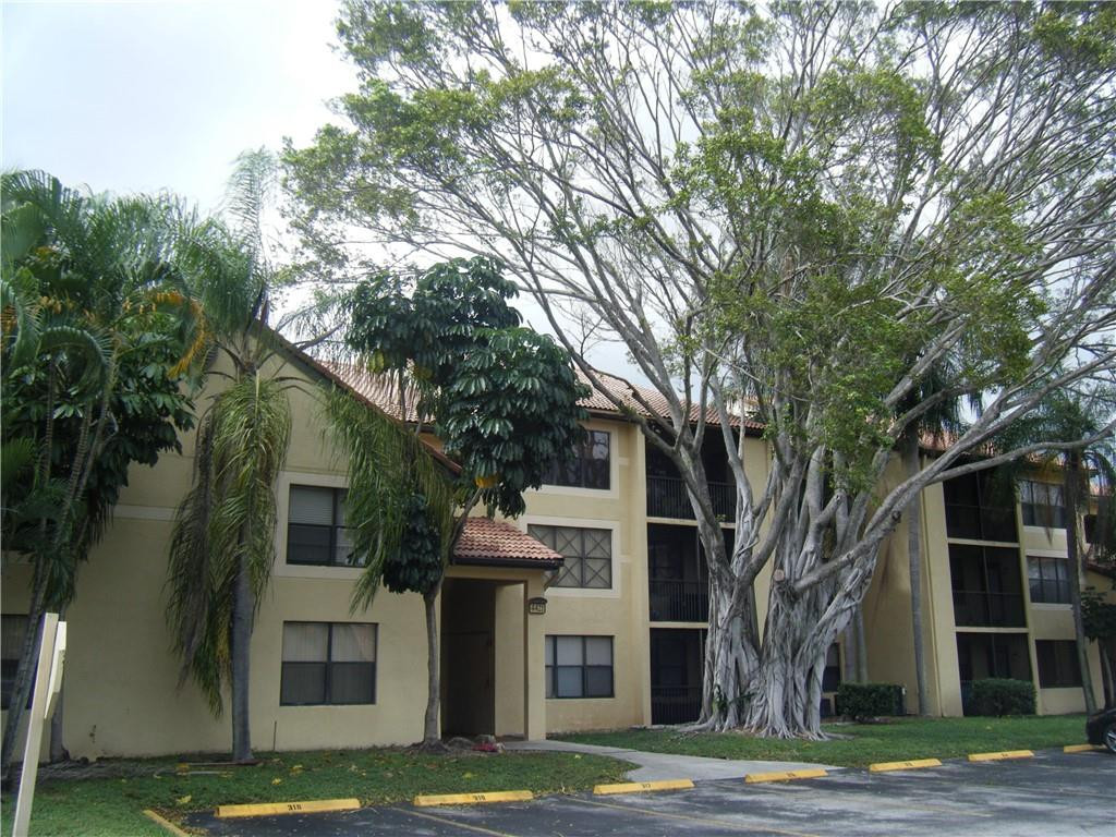 a view of a white house next to a tree with big trees