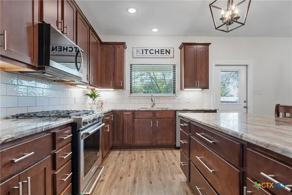 a kitchen with stainless steel appliances granite countertop a sink stove and cabinets