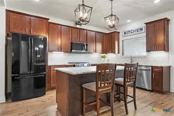 a kitchen with kitchen island granite countertop wooden cabinets and a refrigerator