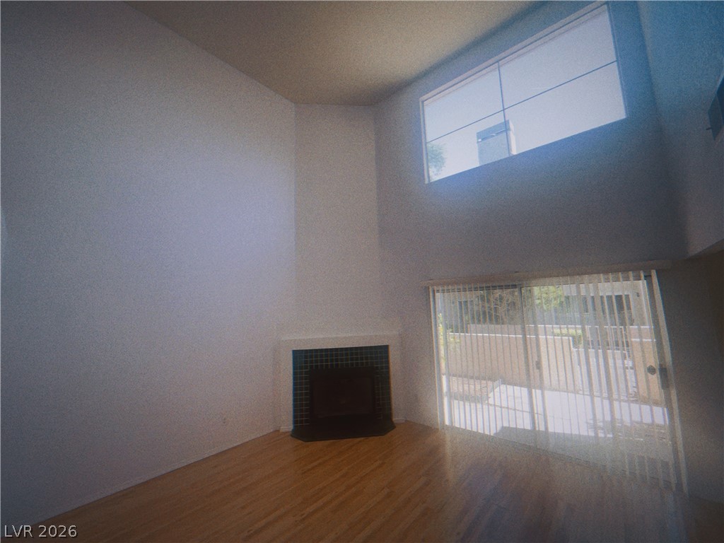 6250 West Flamingo Road, Unit 60 Las Vegas, NV 89103 - Photo 4 of 23 This living space features warm hardwood floors and a modern fireplace, complemented by a soaring window and sliding glass doors.