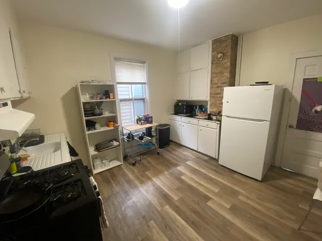 a room with a refrigerator and a wooden floor