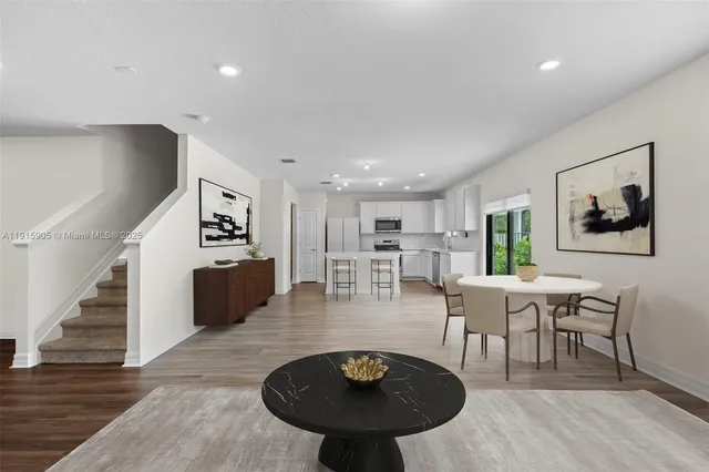 a living room with furniture a table and kitchen view