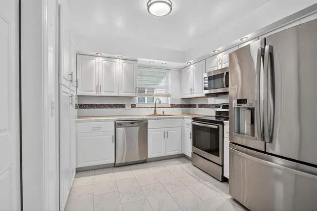 a kitchen with white cabinets and white appliances