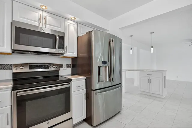 a view of a kitchen with white cabinets and outdoor space