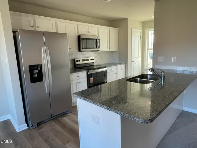 a kitchen with stainless steel appliances granite countertop a sink a microwave a stove and refrigerator