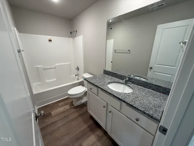 a bathroom with a granite countertop sink toilet and shower curtains