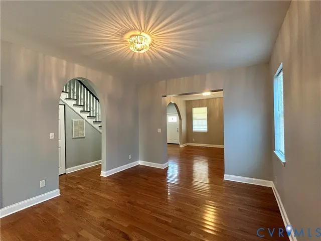 an empty room with wooden floor and chandelier