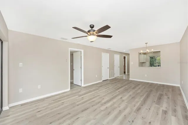 an empty room with wooden floor and ceiling fan