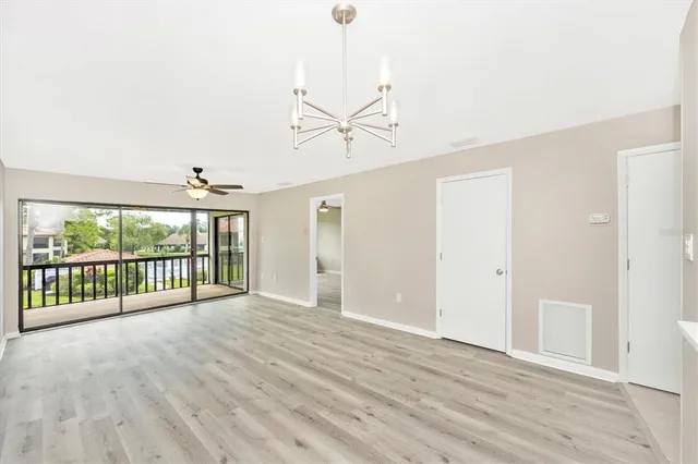 a view of a room with wooden floor fan and windows
