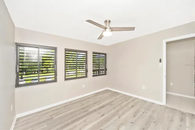 an empty room with wooden floor and windows
