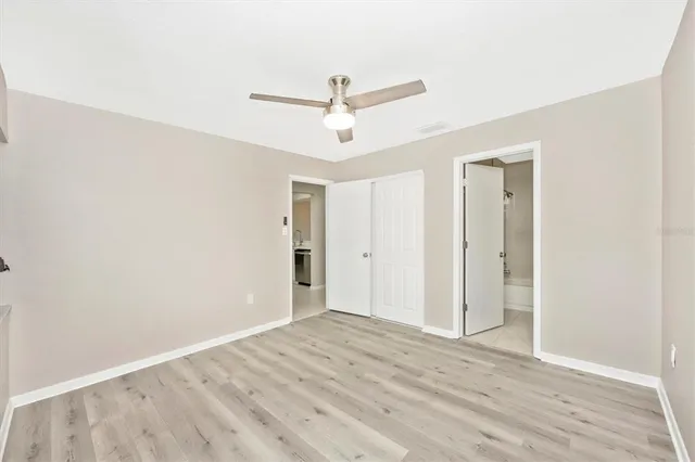 a view of an empty room with wooden floor and ceiling fan