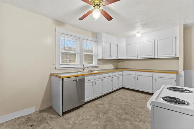 a kitchen with granite countertop a sink cabinets stainless steel appliances and a window