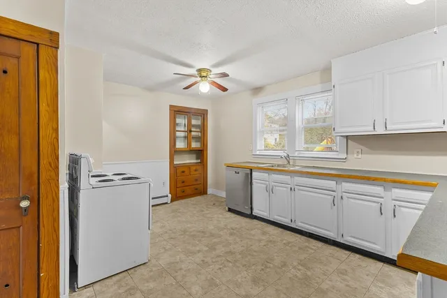 a kitchen with granite countertop a refrigerator a sink a stove and white cabinets