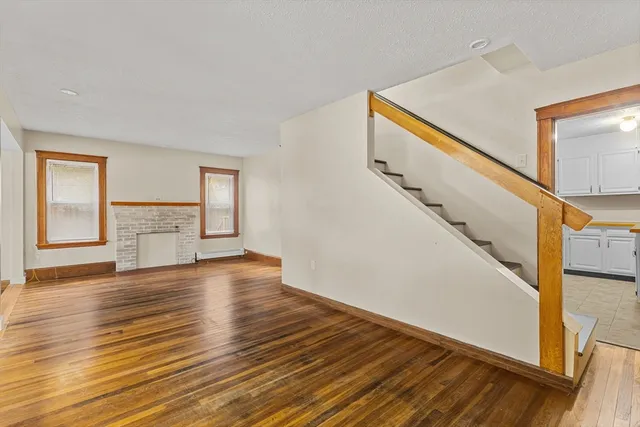 a view of an empty room with wooden floor and stairs