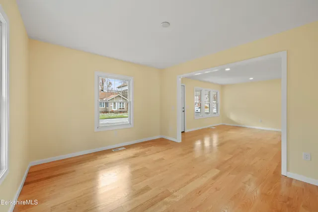 a view of an empty room with window and wooden floor