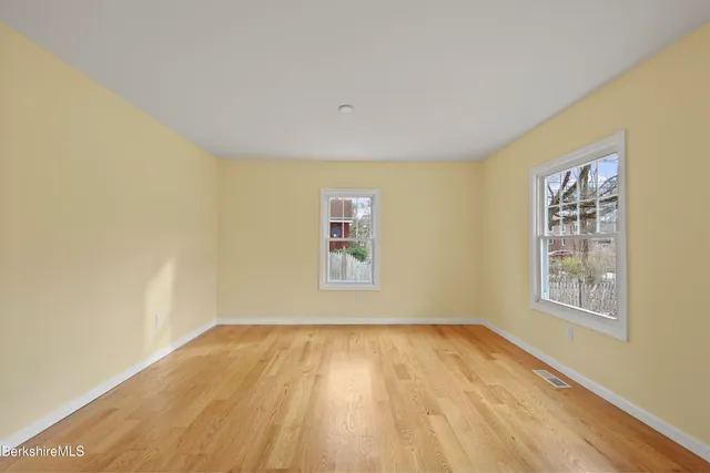 an empty room with wooden floor and windows