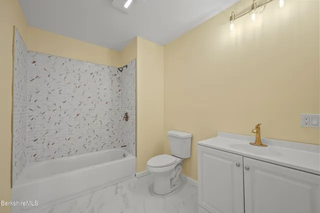 a bathroom with a toilet a sink a mirror and bathtub