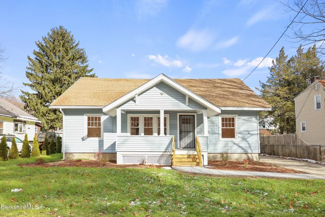 a front view of house with yard and trees in the background