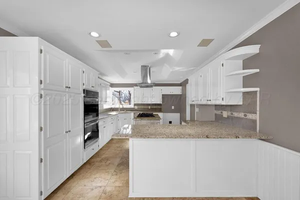 a large kitchen with stainless steel appliances a large counter top a stove and a refrigerator