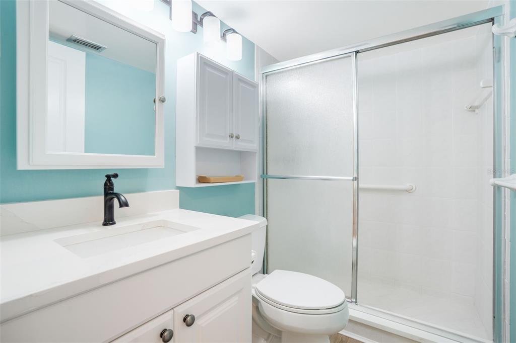 18304 Gulf Boulevard, Unit 105 Redington Shores, FL 33708 - Photo 20 of 33 a bathroom with a sink toilet vanity and shower
