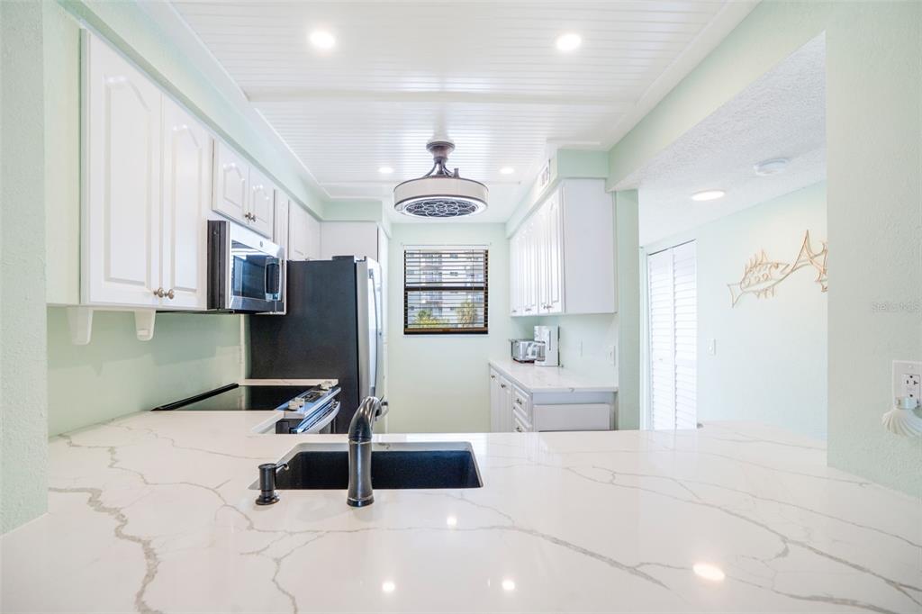 18304 Gulf Boulevard, Unit 105 Redington Shores, FL 33708 - Photo 4 of 33 a room with stainless steel appliances kitchen island granite countertop a refrigerator and a sink