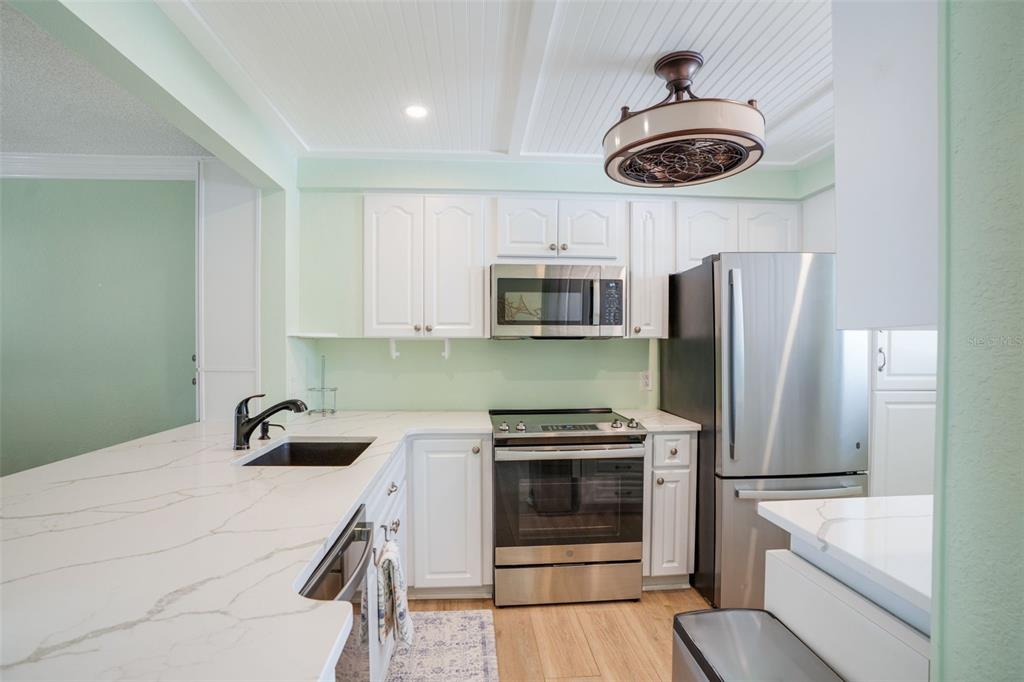 18304 Gulf Boulevard, Unit 105 Redington Shores, FL 33708 - Photo 6 of 33 a kitchen with stainless steel appliances a stove a microwave and a refrigerator