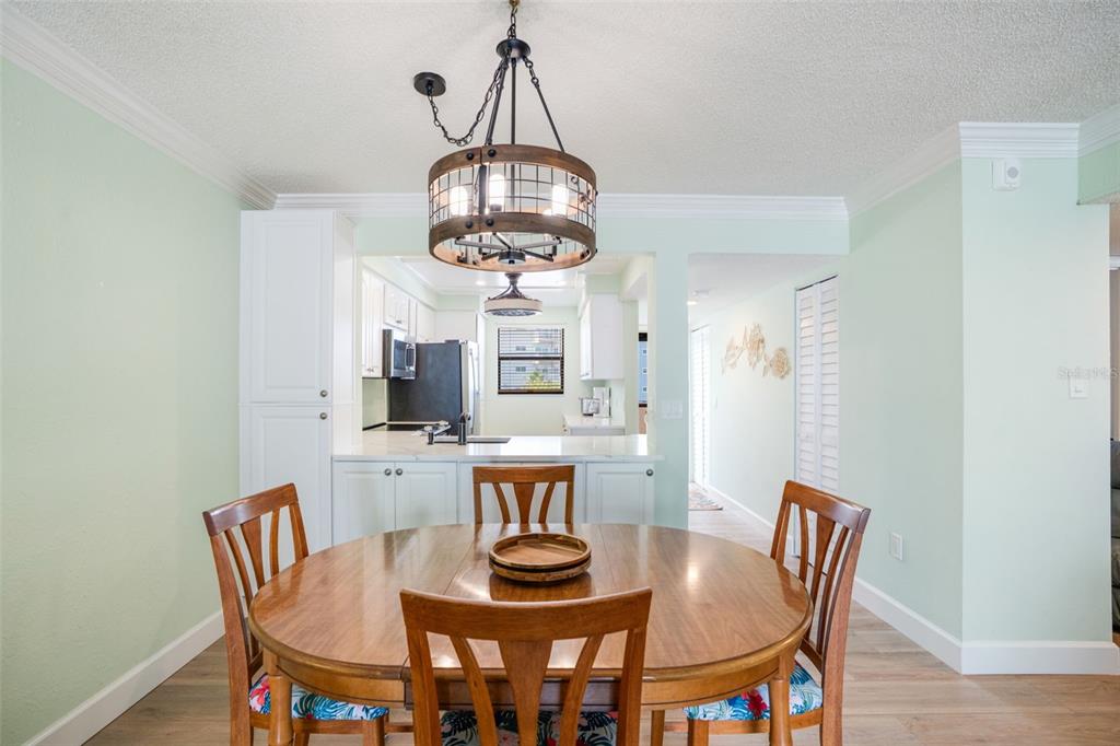 18304 Gulf Boulevard, Unit 105 Redington Shores, FL 33708 - Photo 9 of 33 a view of a dining room with furniture a chandelier and wooden floor