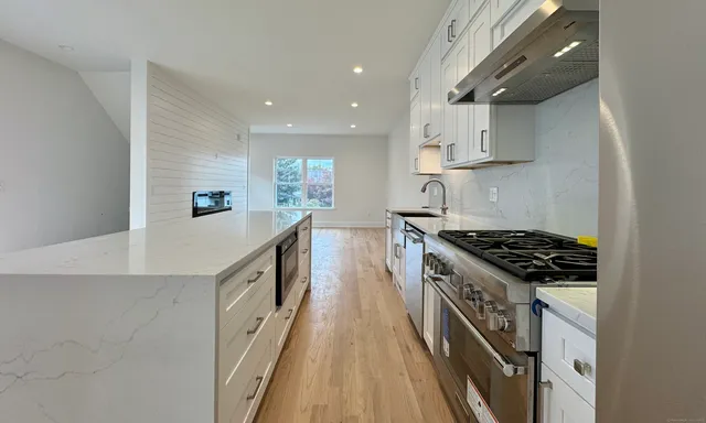 a kitchen with stainless steel appliances a sink a stove top oven a counter space and cabinets