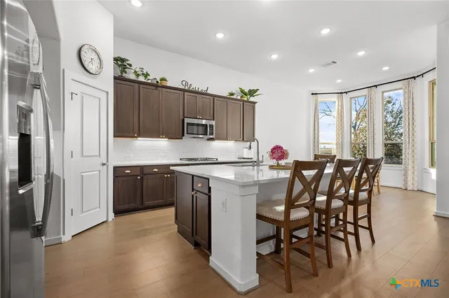 a kitchen with granite countertop a table chairs sink and cabinets