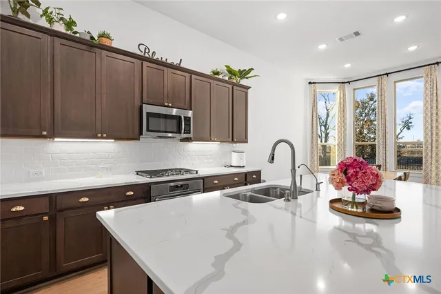 a kitchen with stainless steel appliances a stove a sink a microwave a refrigerator and cabinets