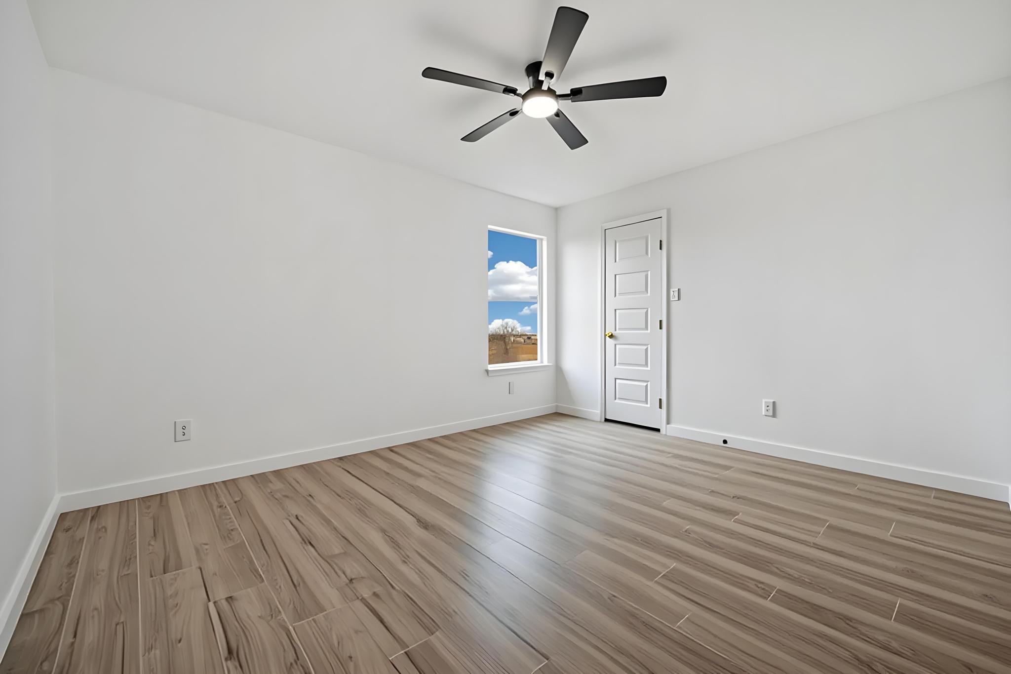 13501 Sierra Wind Lane Elgin, TX 78621 - Photo 12 of 19 Room featuring light wood-finish flooring, white walls, and a multi-paneled door with brass hardware