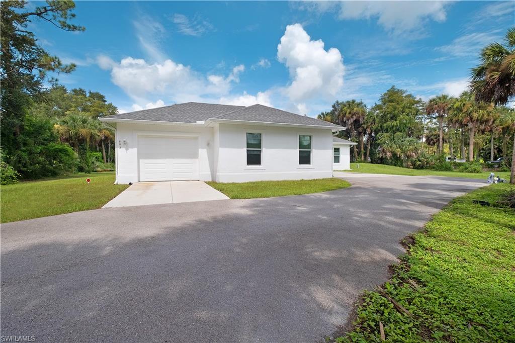 693 7th Street Northwest Naples, FL 34120 - Photo 2 of 32 a front view of a house with a yard and garage