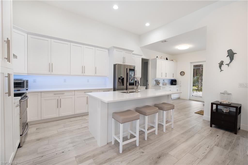 693 7th Street Northwest Naples, FL 34120 - Photo 8 of 32 a kitchen with granite countertop white cabinets and stainless steel appliances